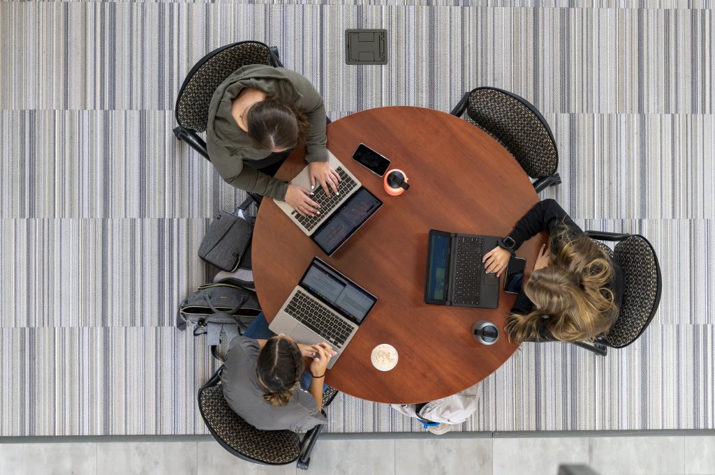 A photo from above featuring three female students working on their laptops in the STEM center.