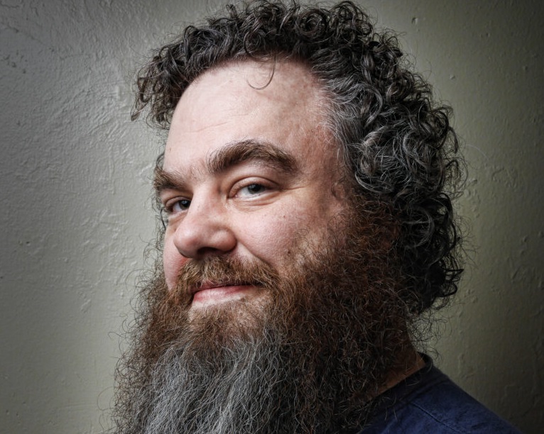 Alumni Patrick Rothfuss is smiling in his headshot photo.