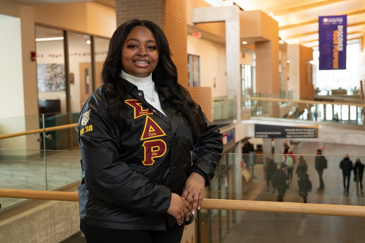 Tahyae Rimson posing in the Dreyfus University Center balcony in her Alpha Phi jacket.