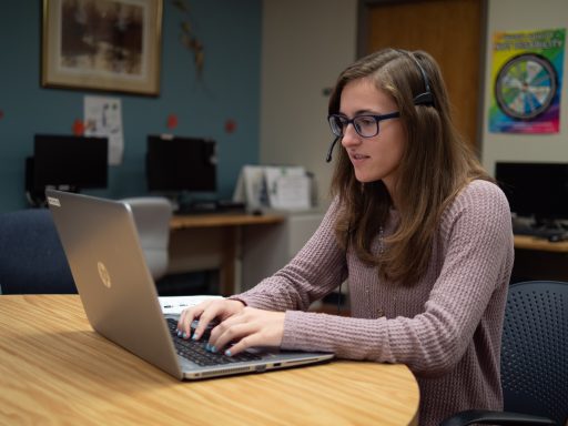 Girl with headphones at laptop on table