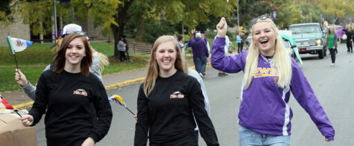 Three students cheering during the homecoming parade.