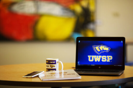 Laptop computer with coffee mug, phone and notenook.