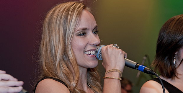 Woman singing into a microphone during a music performance.