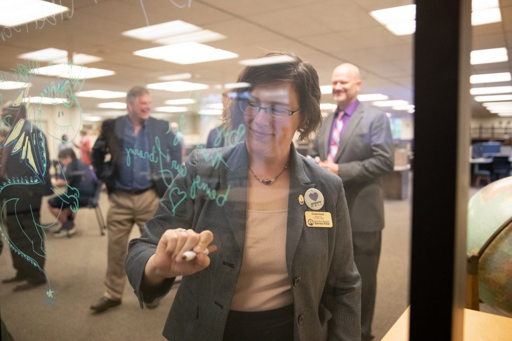 University College Dean Gretel Stock signs a window at the Albertson Hall celebration.