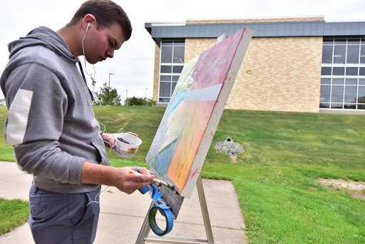 A student painting a canvas outside