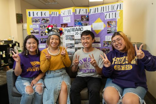 Four students smiling and holding up peace signs.