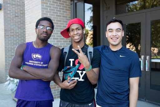 Three students smiling in front of Collins Classroom Center.