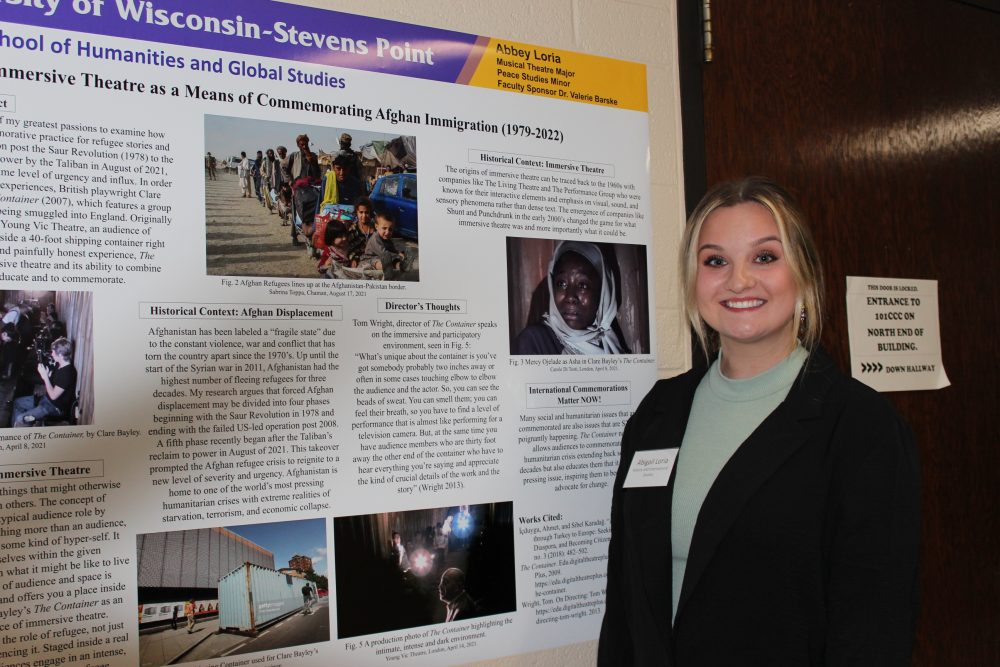 student stands near poster