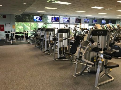 Multiple weight and cardio machines with TVs hanging over the windows.