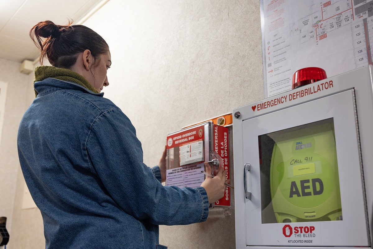 Mac Paszkiewicz installs a Naloxone box with an opioid reversal drug at Baldwin Hall, one of 17 locations at UW-Stevens Point where they are being placed to help prevent overdose deaths.