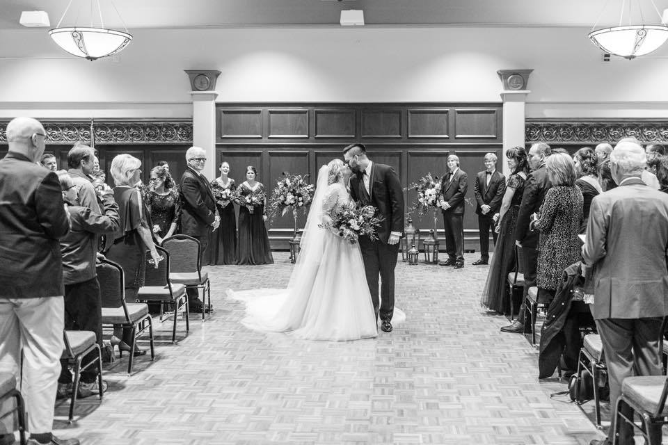 Alumni Room ceremony in black and white, bride and groom kissing