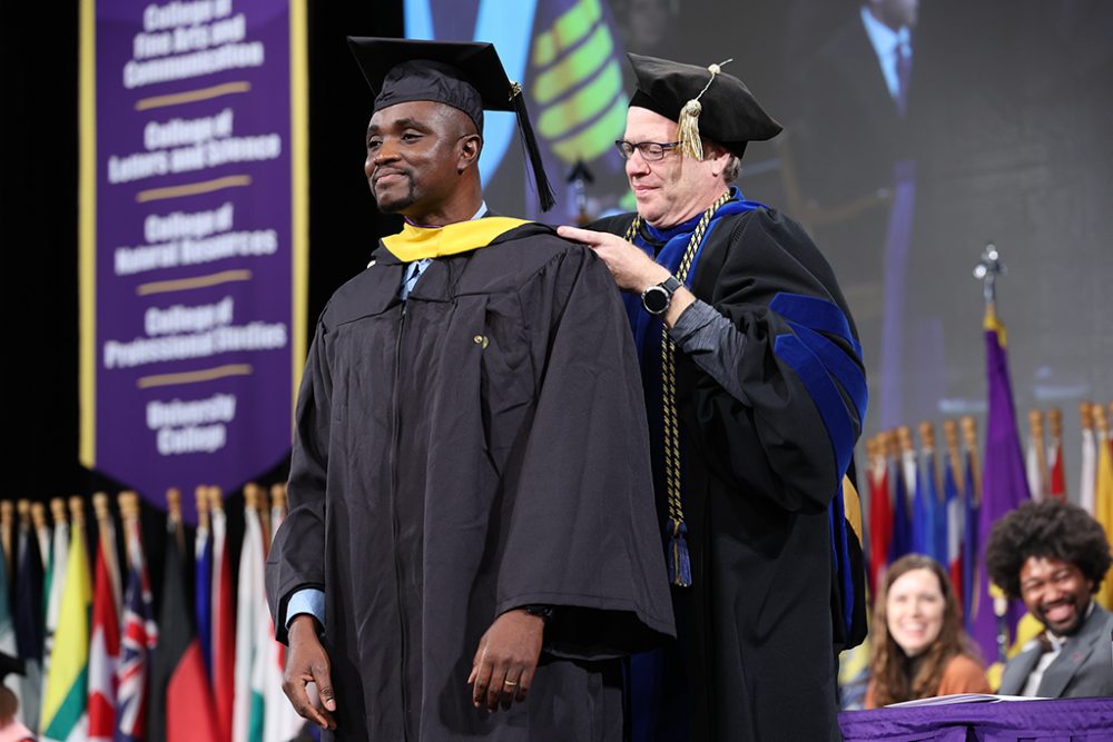 Graduate student being hooded at Commencement by a faculty member.