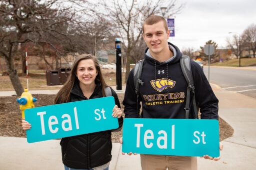 UW-Stevens Point students hold up Teal Street signs from the annual renaming of Fourth Avenue to show support for survivors of sexual assault.