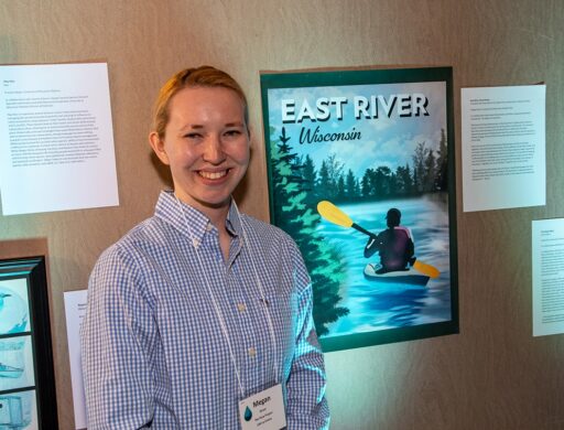 Megan Strom, graphic design major at UW-Stevens Point, poses with a travel poster she created for The Flow Project, which paired student artists and water professionals to create water-inspired art.
