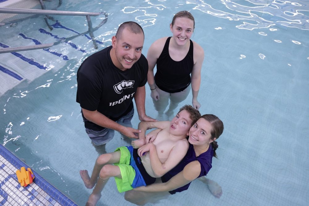 Assistant Professor Paul Haas and students Cierra MacArthur and Paige Franz help a young student in the therapeutic pool.