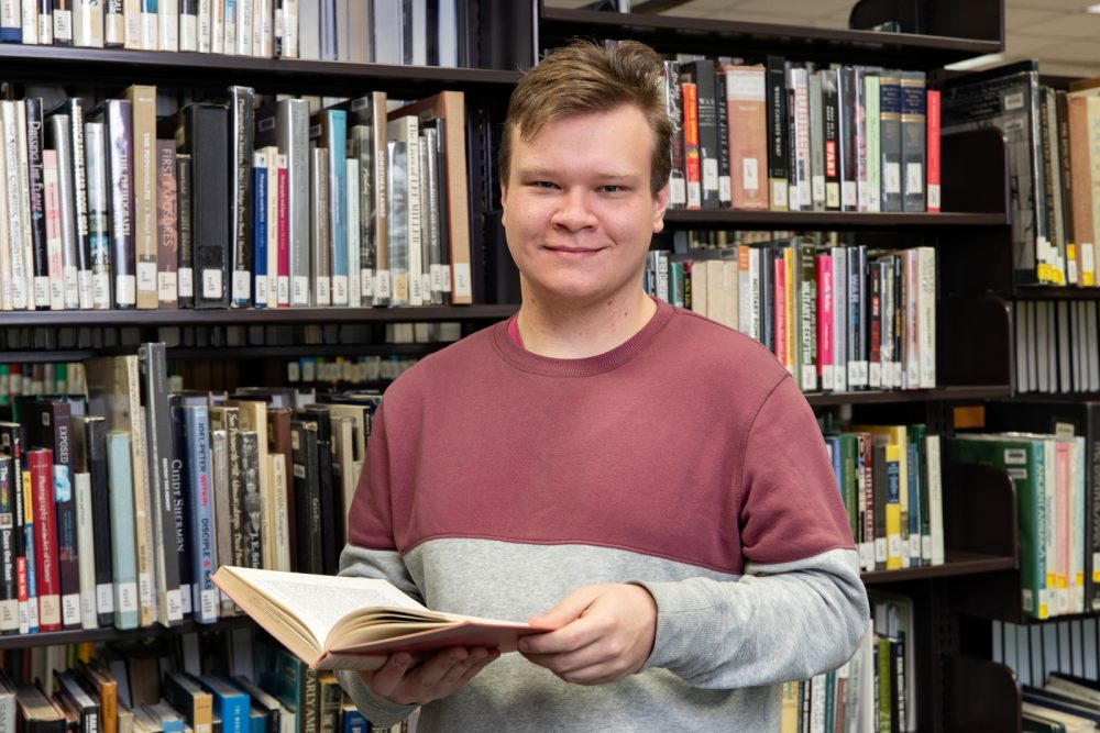 Student in the library holding a book