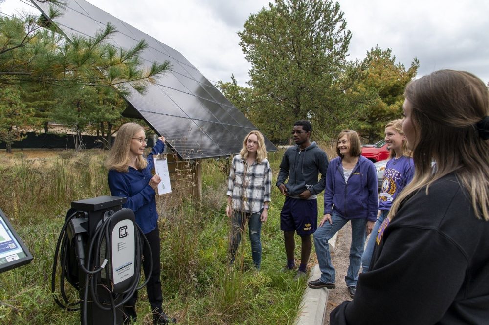 UW-Stevens Point, already a leader in sustainability, is working with Second Nature to further reduce its carbon footprint. Pictured, Associate Professor Kendra Liddicoat, natural resources management, discusses solar powered electric vehicle charging stations with UW-Stevens Point students at Schmeeckle Reserve, a campus natural area.
