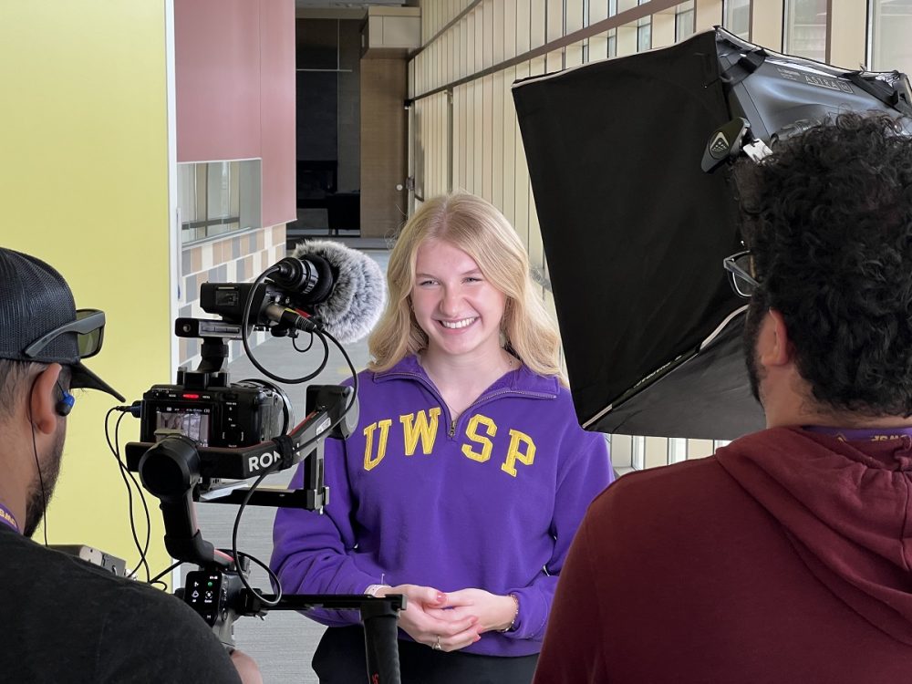 Biochemistry student Elliot Becker films her spot in The Suites residence hall.