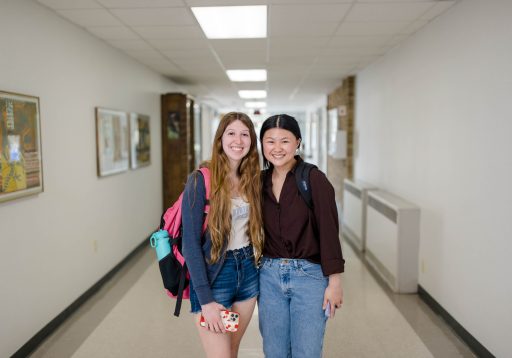 Two students standing in a hallway smiling