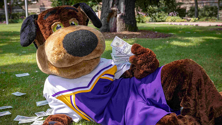 Stevie Pointer laying down on his side on the front lawn of Old Main with money in hand.