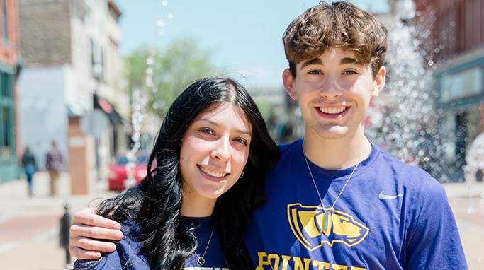 Two student in front of a fountain in downtown Stevens Point