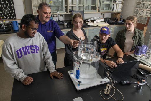 Students and a professor working with chemistry equipment
