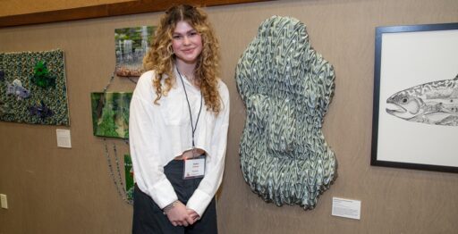 UW-Stevens Point student Sophia Semersky stands by her handsewn textile sculpture, “Downstream,” at last year’s Flow Project Art Exhibit. Photo by Doug Moore.